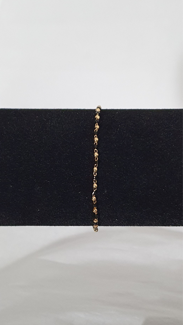 Bracelet fin plaqué or avec des perles noires sur présentoir