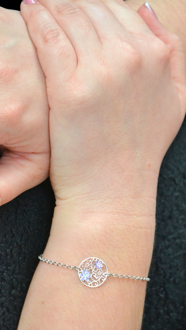 Bracelet argent rhodié 925 millièmes représentant des fleurs bleues sur modèle