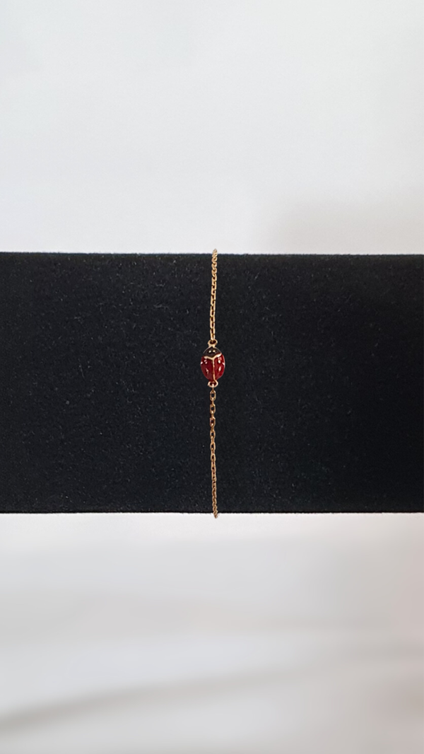 Bracelet plaqué or en forme de coccinelle rouge à pois noirs sur présentoir