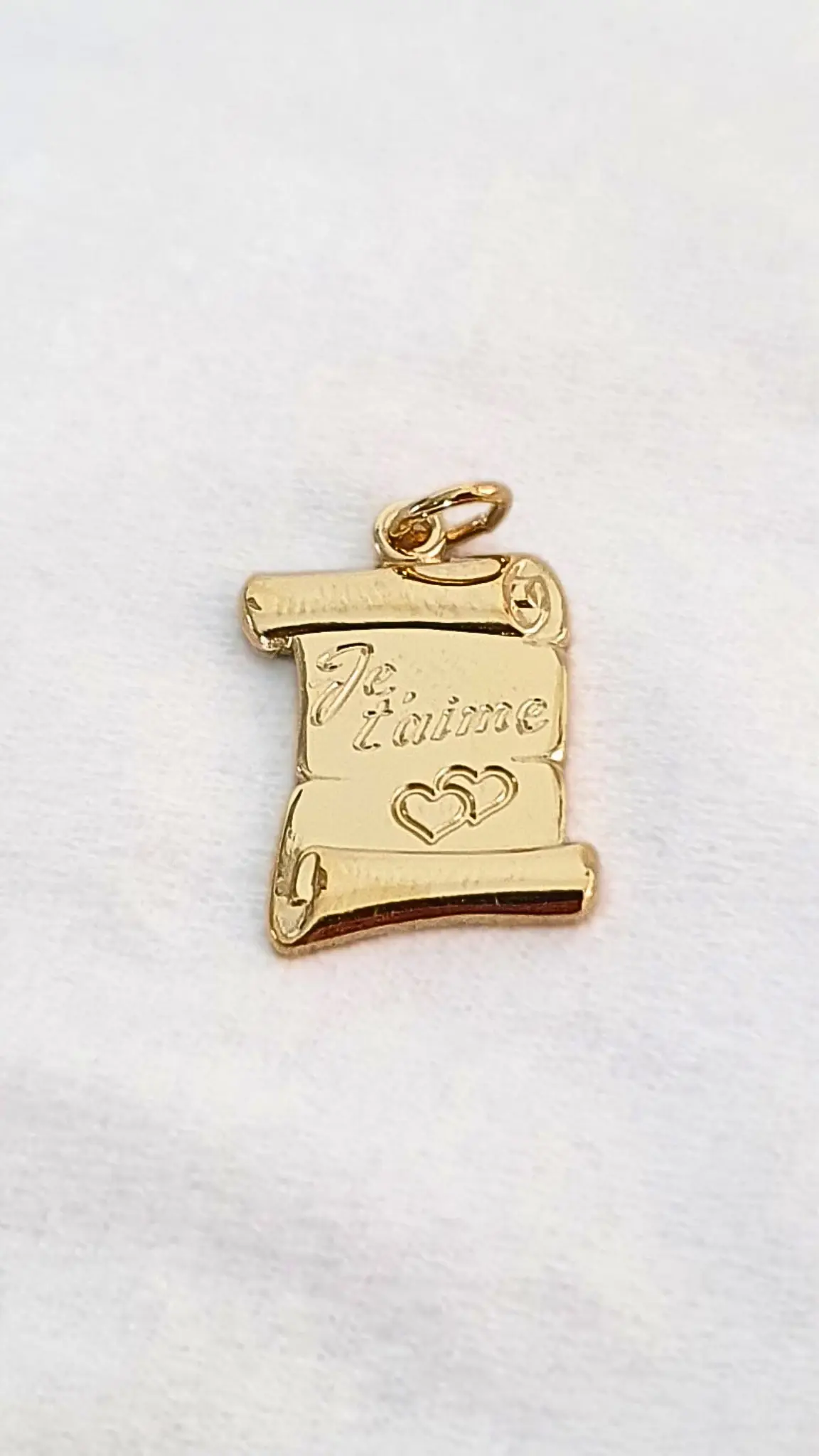 Pendentif d'un parchemin en or avec écrit dessus "Je t'aime" avec deux cœurs gravés en présentation