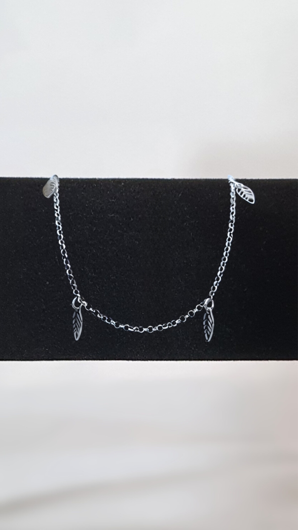 Bracelet en argent rhodié 925 millièmes constitué de petites feuilles en breloque sur présentoir